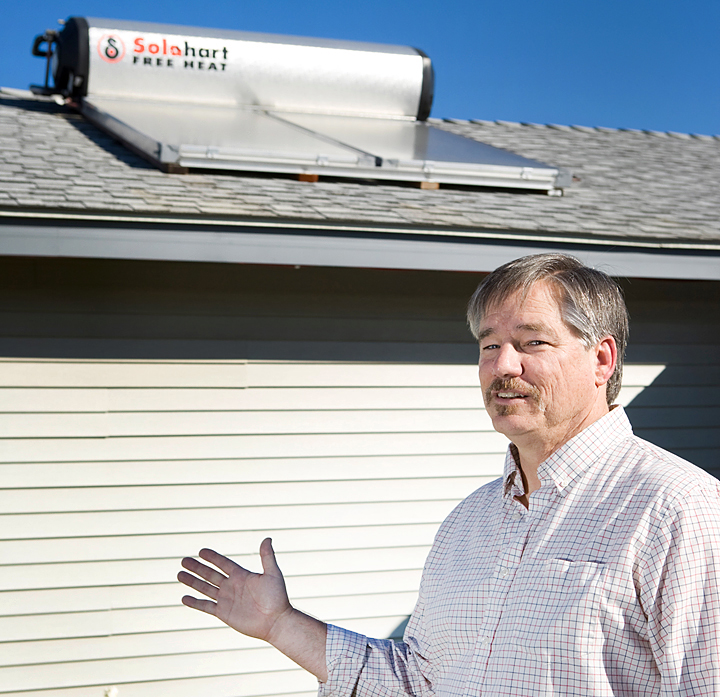 Man pointing to solar water heating system on rooftop