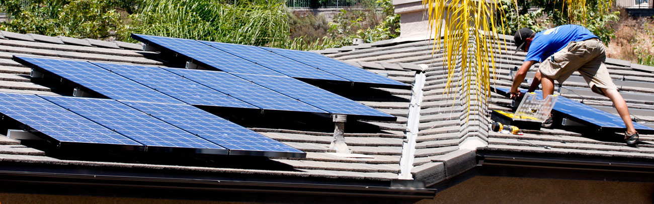 Person installing solar panels on rooftop