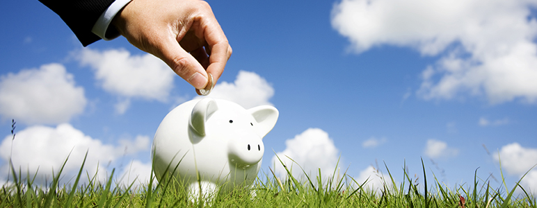 Photo of hand putting coin in piggy bank