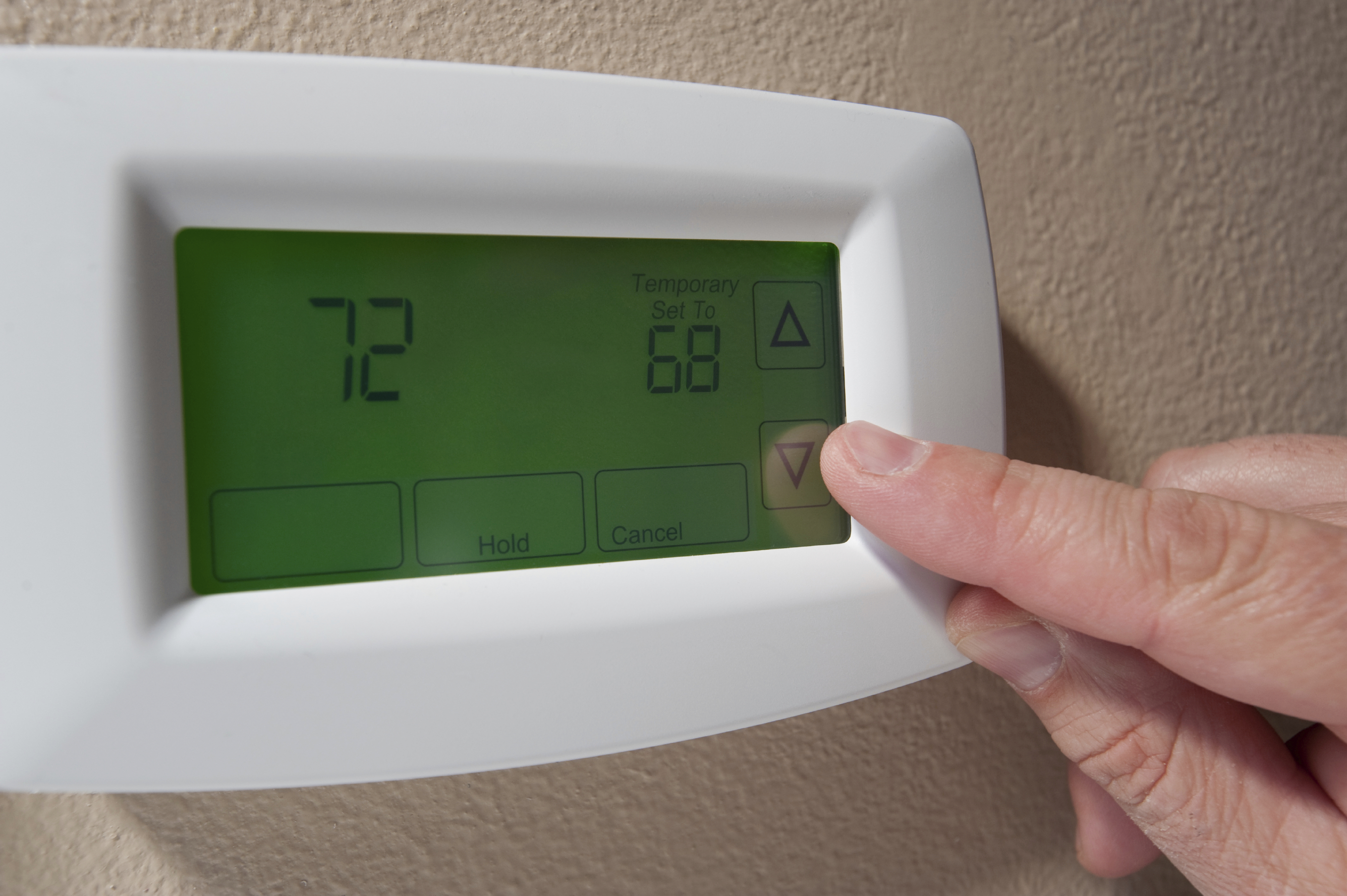 Photo of finger adjusting home thermostat