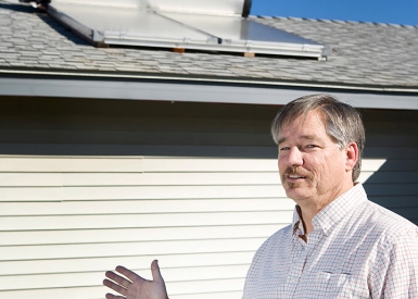 Man pointing to solar water heating system on rooftop